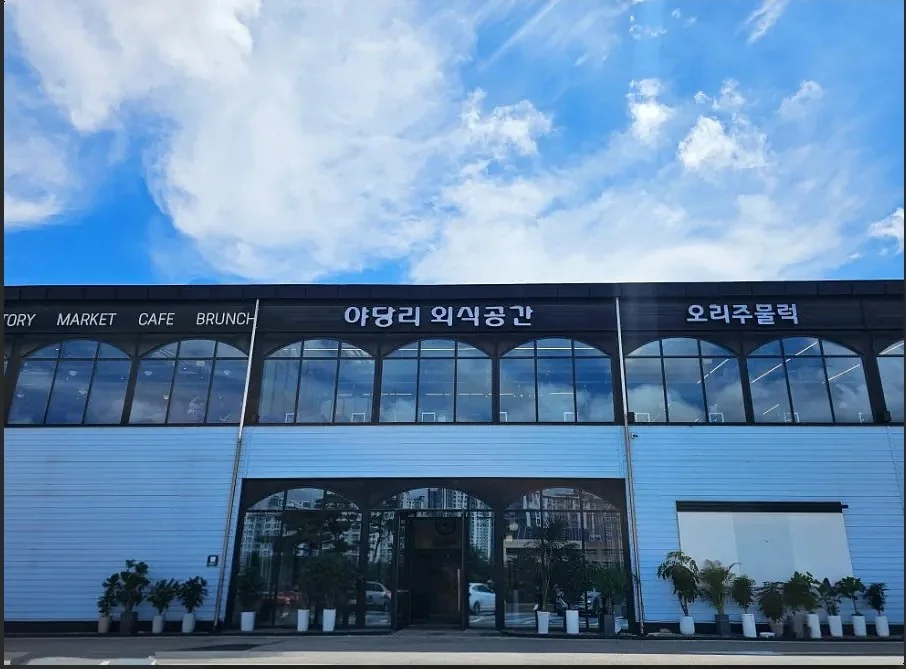 파란 하늘 아래 대로변 매장 외관과 주차장